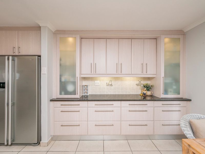 A well-maintained kitchen featuring light wood-finish cabinetry, granite countertops, a tiled backsplash, and integrated under-cabinet lighting.