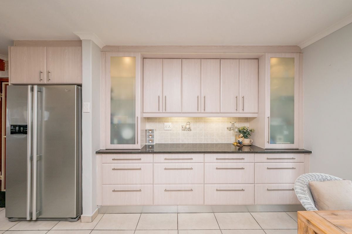 A well-maintained kitchen featuring light wood-finish cabinetry, granite countertops, a tiled backsplash, and integrated under-cabinet lighting.