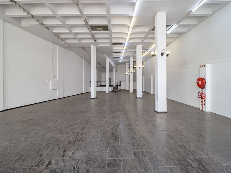 Spacious open-plan commercial unit featuring a distinctive waffle slab ceiling, structural columns, tiled flooring, and essential fire safety equipment.