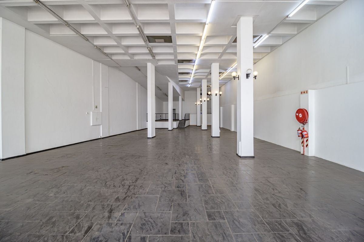 Spacious open-plan commercial unit featuring a distinctive waffle slab ceiling, structural columns, tiled flooring, and essential fire safety equipment.