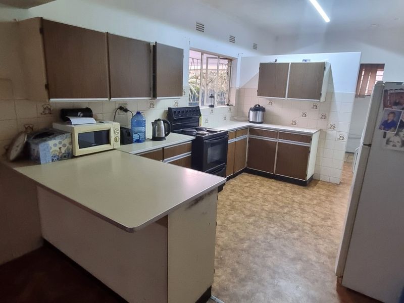 A dated kitchen featuring original cabinetry, laminate countertops, and a freestanding oven, offering significant potential for a modern renovation.