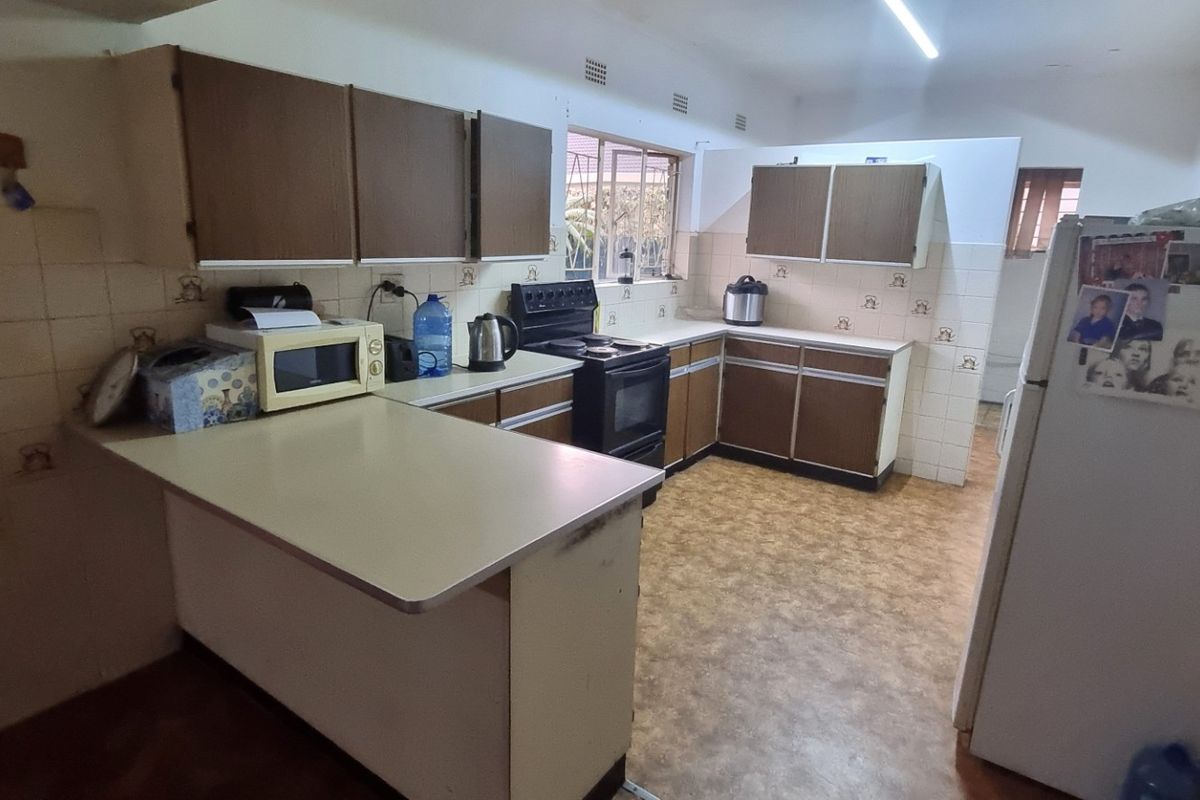 A dated kitchen featuring original cabinetry, laminate countertops, and a freestanding oven, offering significant potential for a modern renovation.