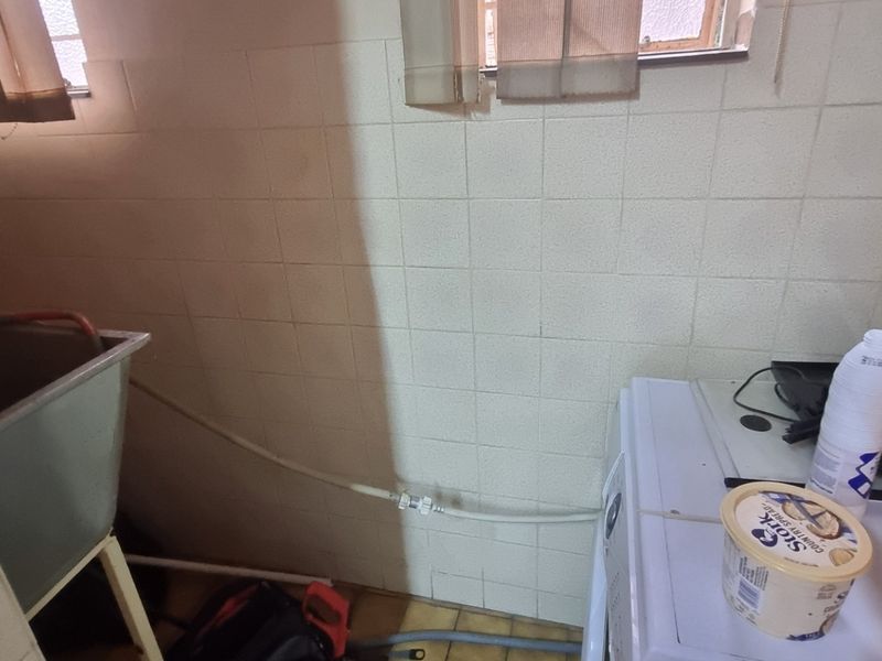 A functional laundry area featuring tiled walls and a utility sink, requiring cosmetic updates to improve the overall condition and aesthetic appeal.