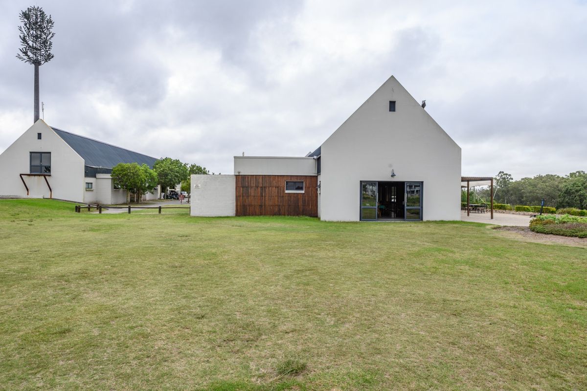 A view of the rear exterior of the property featuring a large lawn, pitched roof architecture, and timber-clad accents.