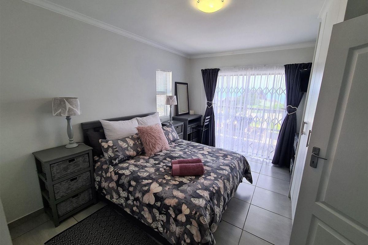 A well-maintained bedroom featuring tiled flooring, built-in cupboards, and a sliding door providing access to an outdoor area with security gate.