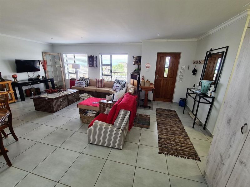 Spacious open-plan living area featuring neutral tiled flooring, recessed lighting, and a solid timber front entrance door with natural light.