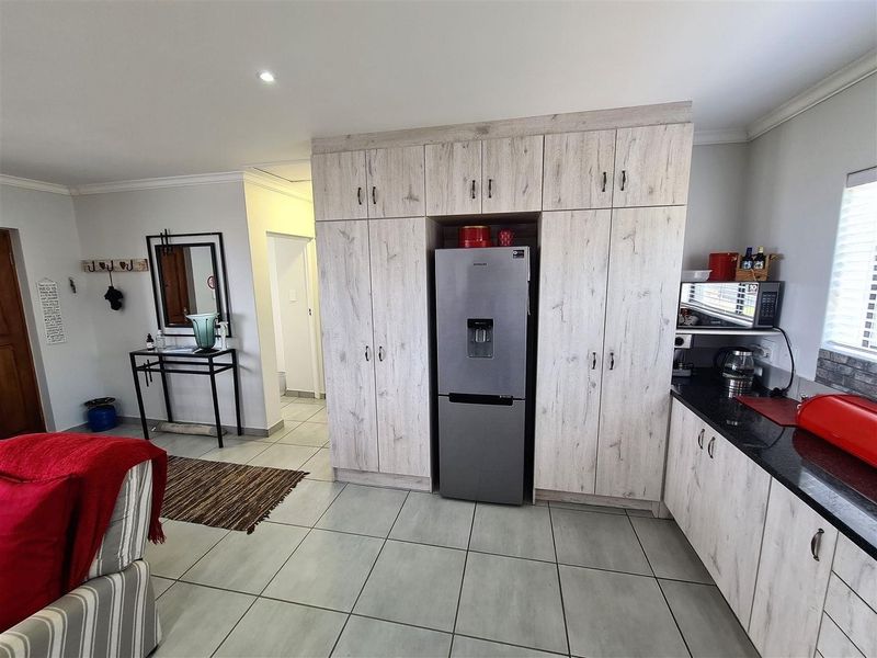 Modern kitchen featuring light wood-grain cabinetry, dark granite countertops, and neutral floor tiles, offering a clean and functional workspace.