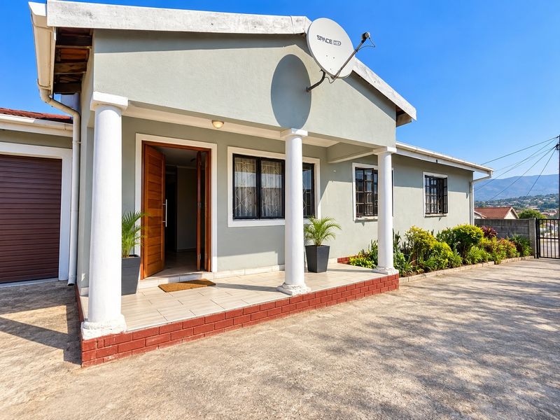 Front exterior view of the house featuring a covered porch with decorative columns, tiled patio, and a concrete driveway.