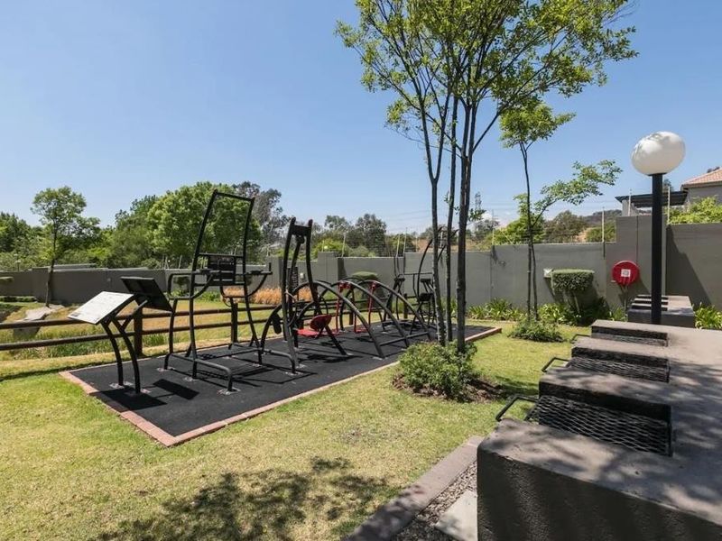 Outdoor communal area featuring fixed gym equipment, built-in braai facilities, and well-maintained garden space within a secure complex.
