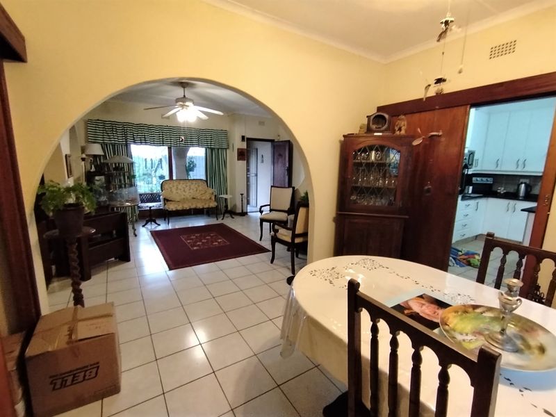 Open plan living and dining area featuring tiled flooring, a central archway, and a view into the adjacent kitchen space.