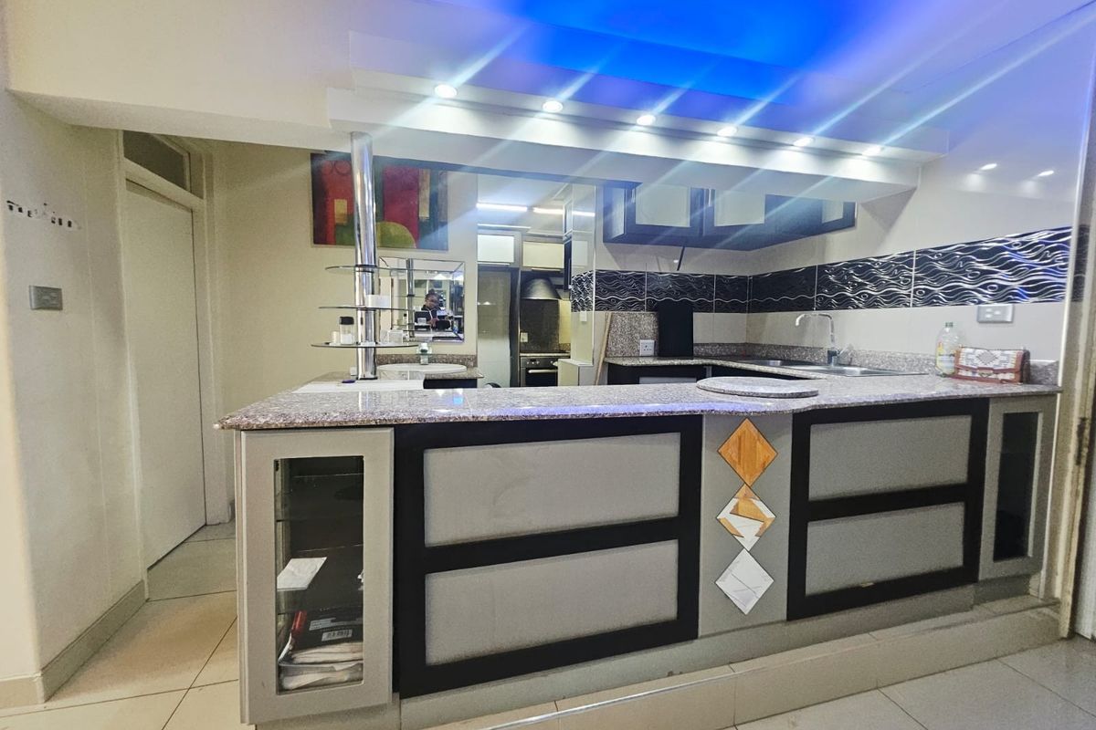 A functional kitchen featuring granite countertops, a breakfast bar, and integrated cabinetry with a tiled backsplash and modern recessed lighting.