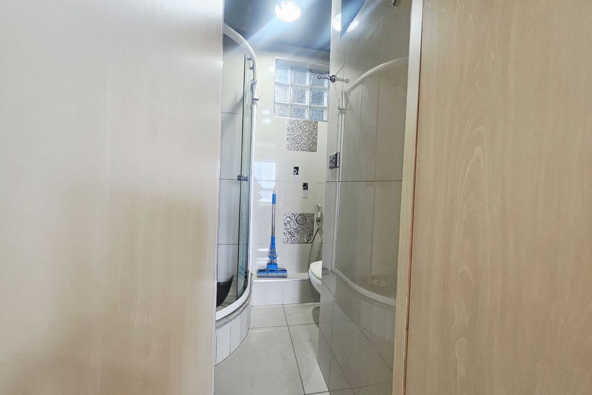 A compact bathroom featuring a glass shower enclosure, tiled walls, and a glass block window for natural light.