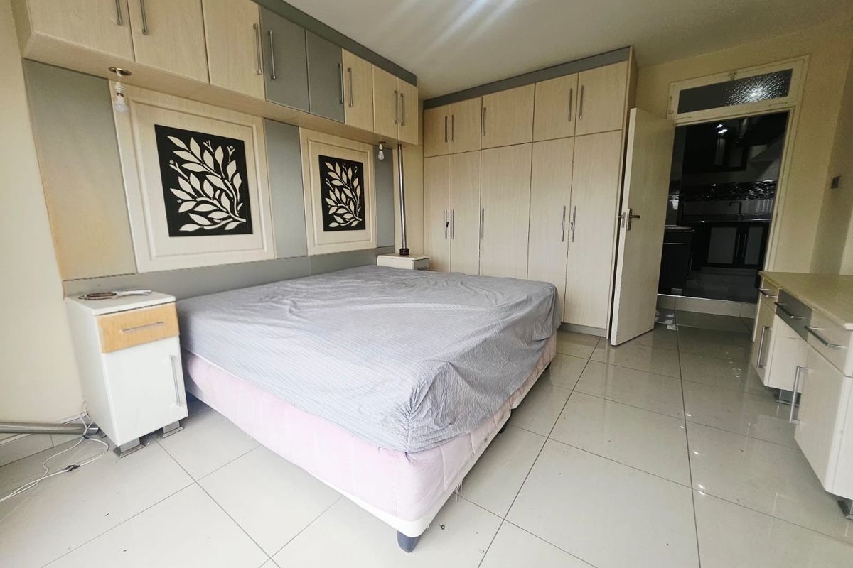 A bedroom featuring extensive built-in cabinetry, overhead storage units, and light-colored tiled flooring, offering ample storage space.