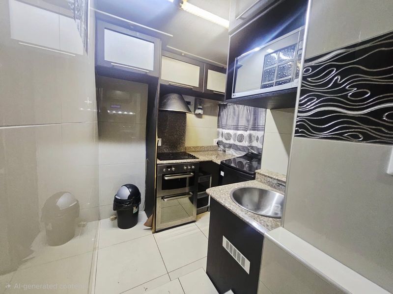Compact kitchen featuring built-in cabinetry, granite countertops, a stainless steel sink, and a freestanding oven with an extractor fan.