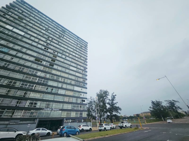 Exterior view of Carlton Towers apartment building showing the multi-story facade, balconies, and street-level access.