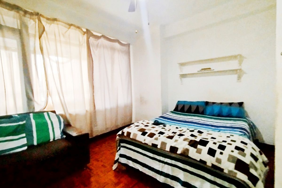 A bedroom featuring parquet flooring, a ceiling fan, and built-in wall shelving, with large windows allowing for natural light.