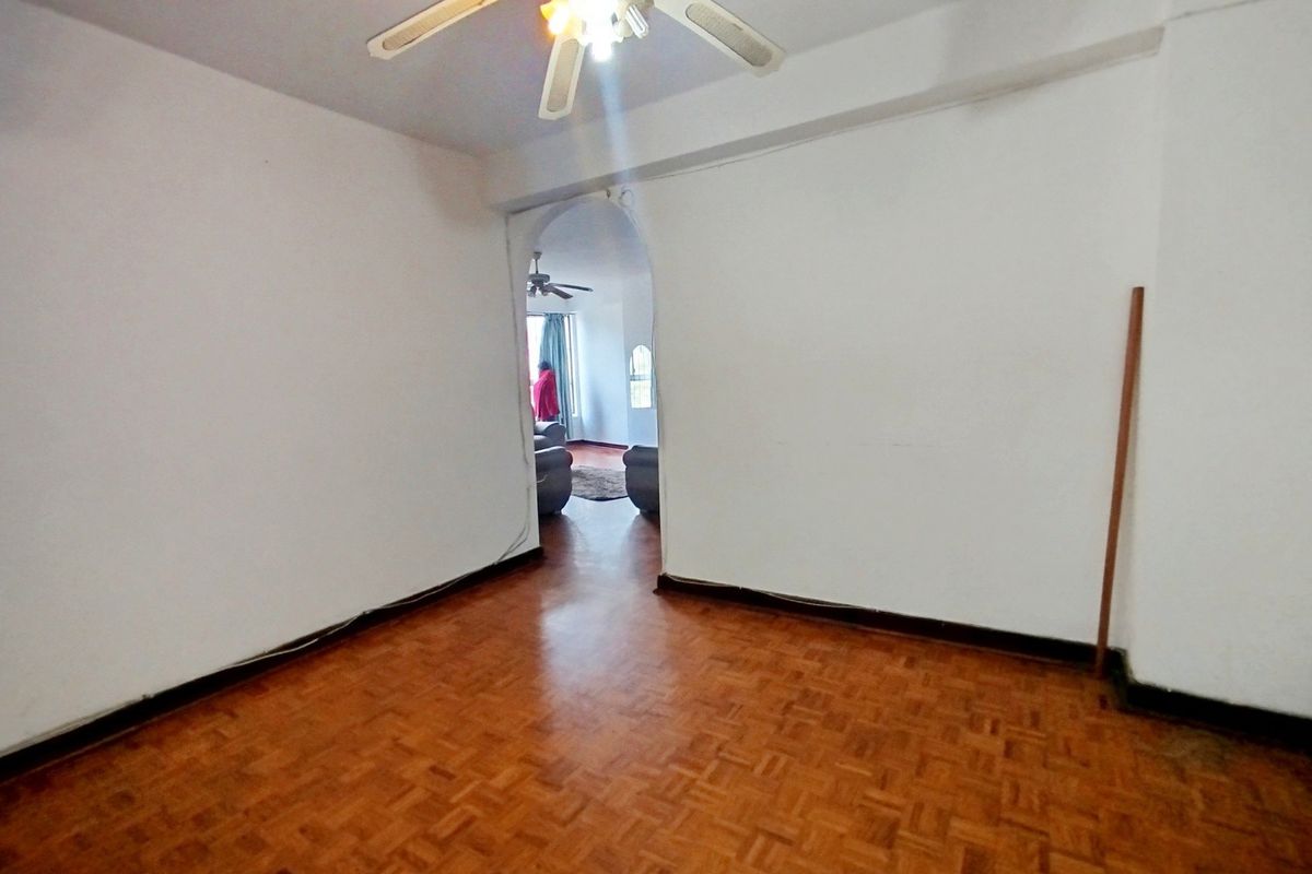 An empty living room featuring classic parquet flooring, a ceiling fan, and an arched entryway leading to an adjacent space.