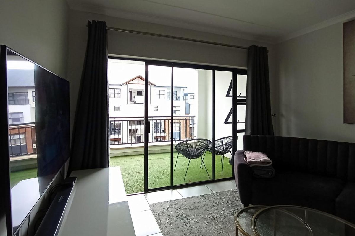 A living room featuring tiled flooring and a large sliding glass door providing access to an outdoor balcony area.