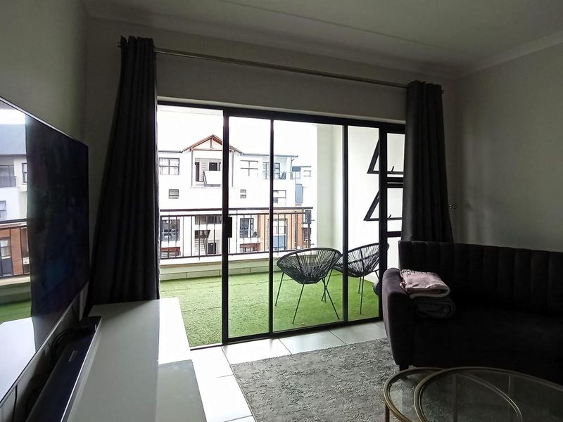 A living room featuring tiled flooring and a large sliding glass door providing access to an outdoor balcony area.