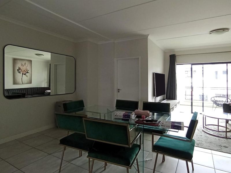 An open-plan living and dining area featuring tiled flooring, neutral walls, and large sliding glass doors providing access to the balcony.