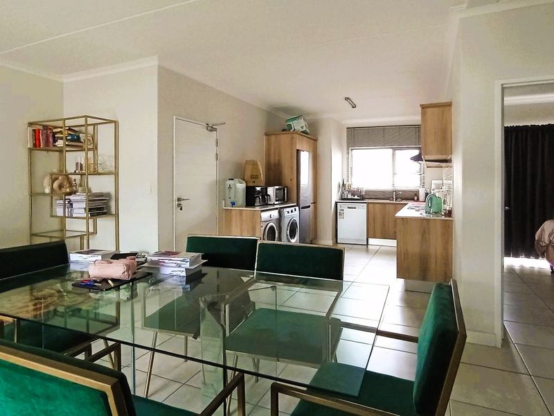 Open-plan living and dining area featuring tiled flooring and a functional kitchen with built-in cabinetry, seamlessly connecting to the adjacent bedroom space.