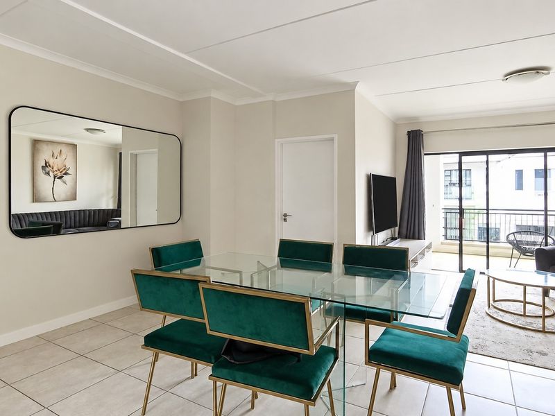 Bright open-plan living and dining area featuring neutral tiled flooring, modern finishes, and direct access to a private balcony through sliding glass doors.