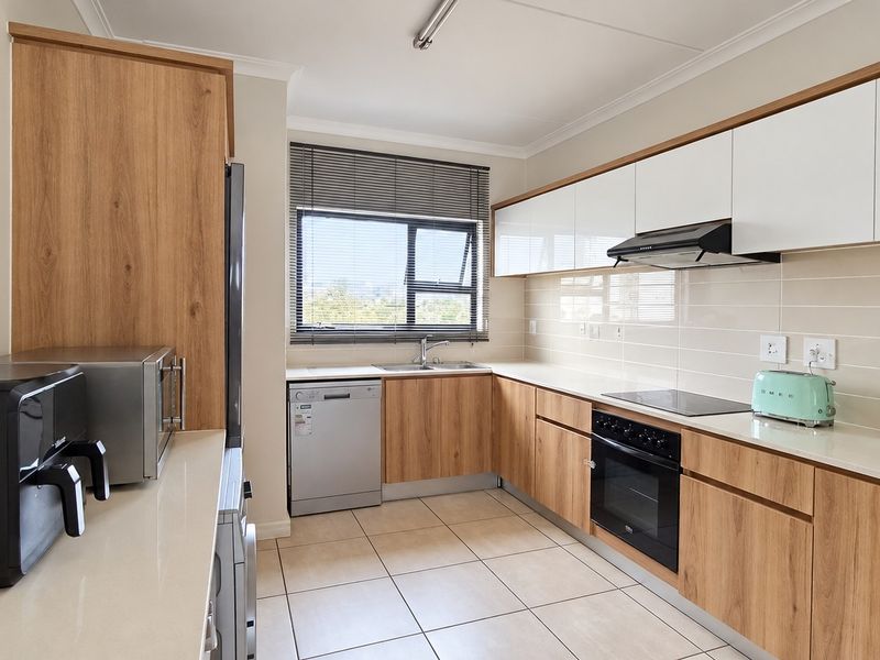 Modern kitchen featuring wood-grain cabinetry, stone countertops, tiled backsplash, and integrated appliances including an oven, hob, and extractor fan.