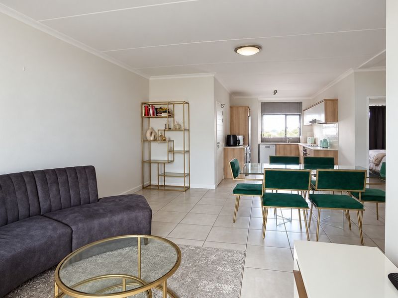 Spacious open-plan living and dining area featuring tiled flooring and a modern kitchen with built-in cabinetry and functional workspace.