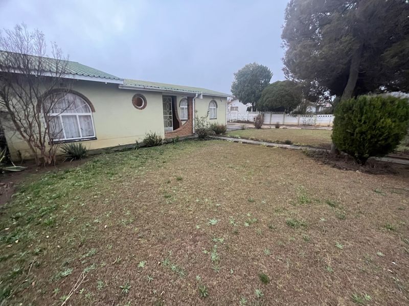 Front view of a single-story house featuring arched windows, a distinctive porthole window, and a front garden area with a concrete pathway.