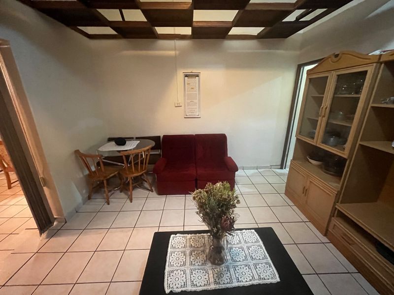 A living room featuring ceramic tile flooring and a distinctive coffered wooden ceiling, offering a functional space with traditional architectural elements.