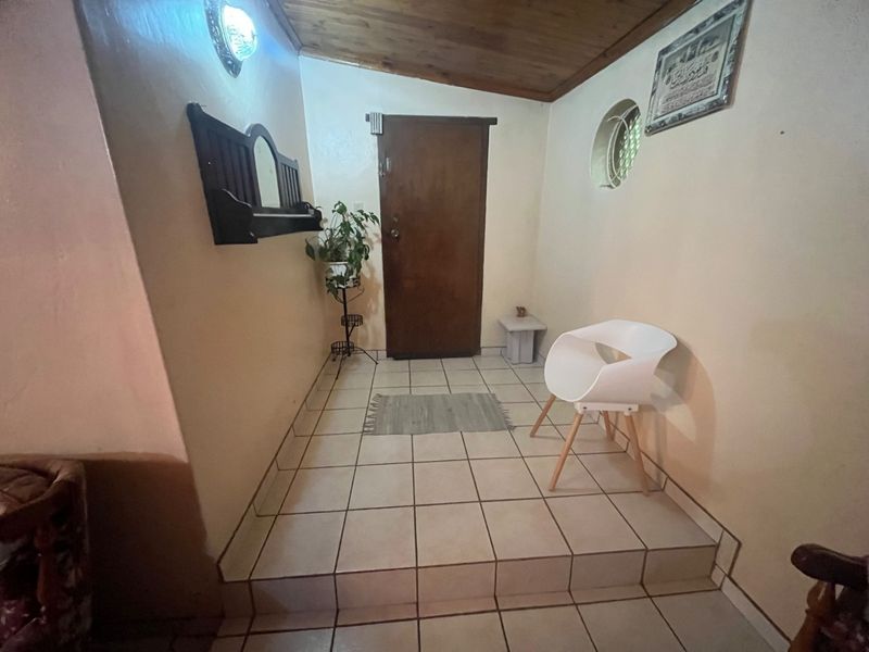 An entry area featuring tiled flooring, a timber-clad ceiling, and a circular window, providing a functional and welcoming transition space into the home.