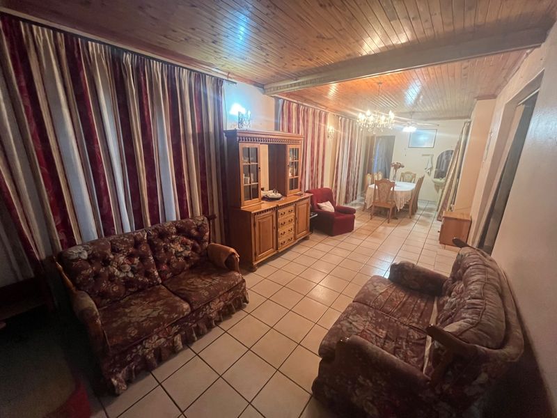 Open plan living and dining area featuring ceramic floor tiles and a timber tongue and groove ceiling.
