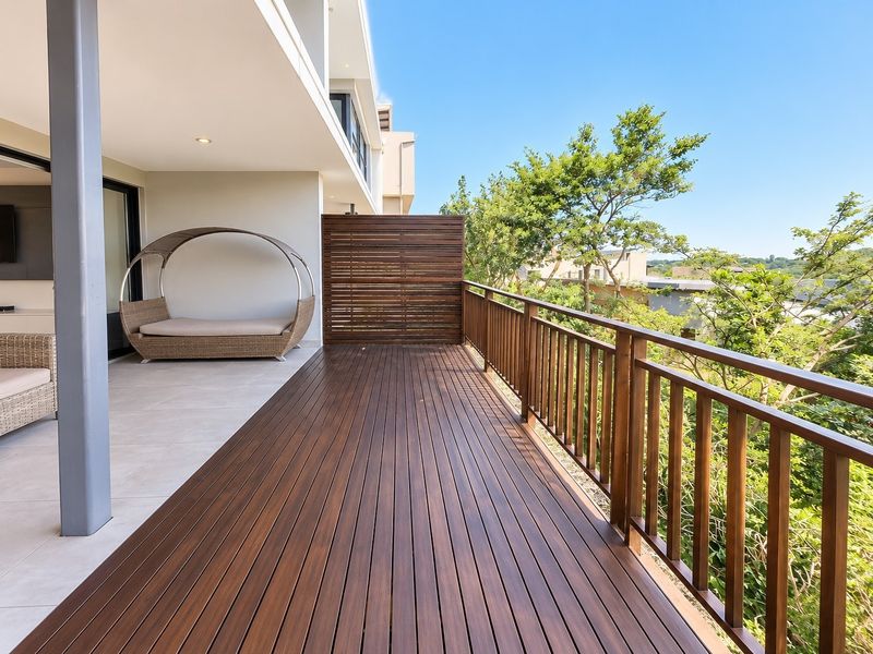 Spacious covered balcony featuring high-quality timber decking, a timber balustrade, and a privacy screen, offering an elevated outdoor living space.