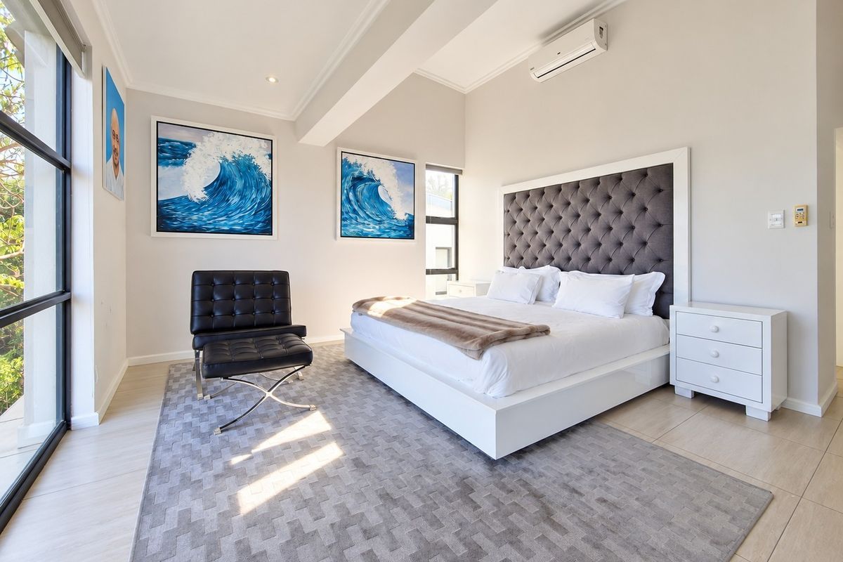 Spacious, well-lit bedroom featuring tiled flooring, large windows, and a split-system air conditioner, offering a clean and modern aesthetic.
