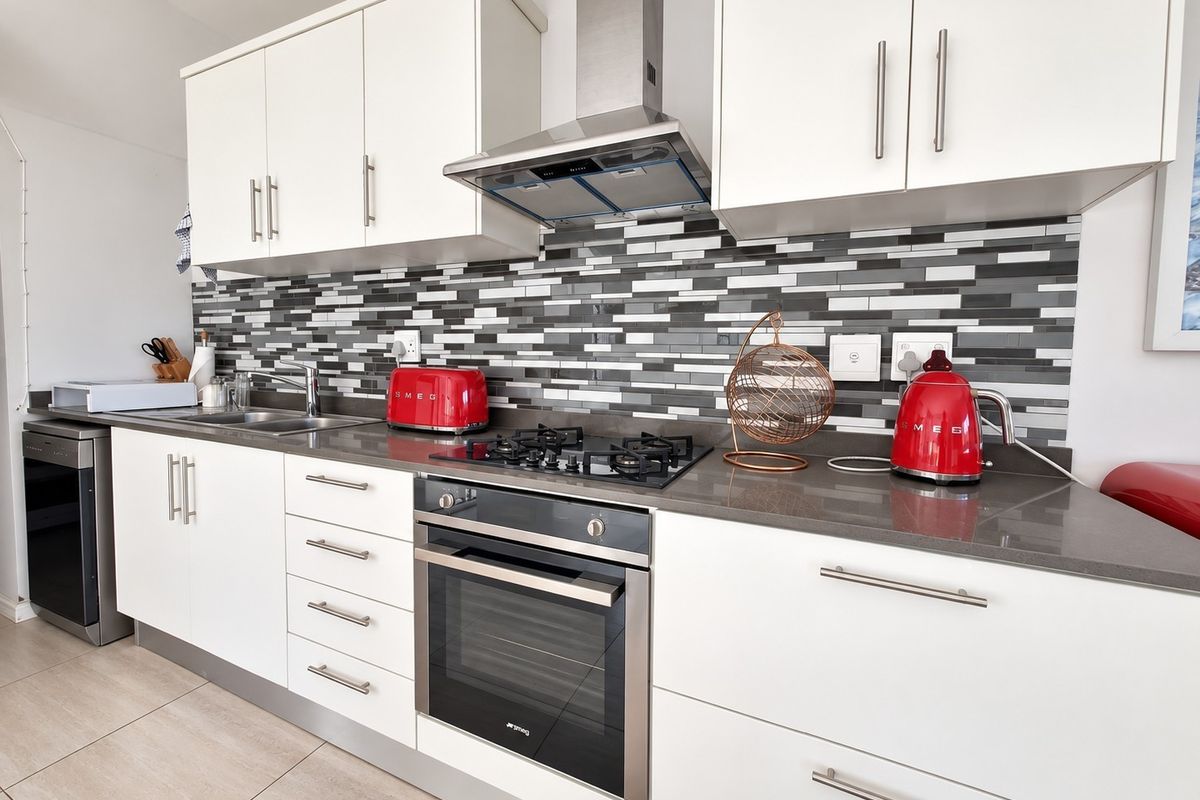 Modern kitchen featuring white cabinetry, stone countertops, a gas hob with extractor fan, and a contemporary mosaic tile backsplash.