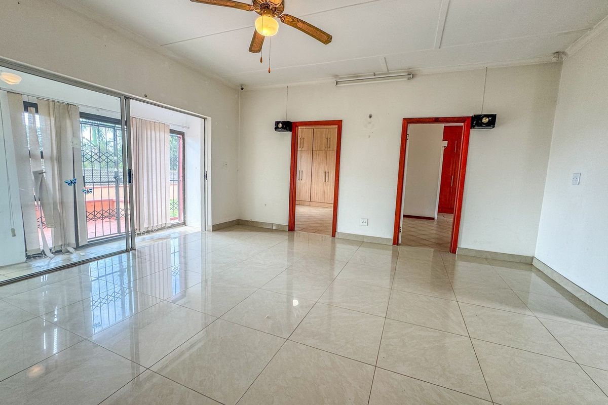 Spacious living area featuring large sliding glass doors, tiled flooring, a ceiling fan, and direct access to adjacent rooms with built-in storage.