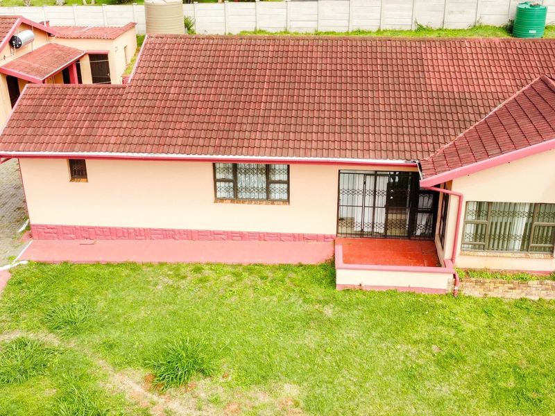 Aerial view of the property showing the main house with a tiled roof, security bars on windows, and surrounding garden area.