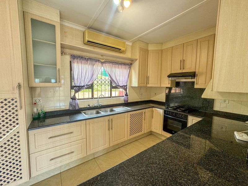 A functional kitchen featuring granite countertops, built-in oven, gas hob, and ample cabinetry, providing a practical workspace for daily cooking and meal preparation.