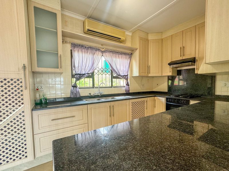 A functional kitchen featuring granite countertops, ample built-in cabinetry, a double sink, and integrated appliances, offering a practical layout for daily use.