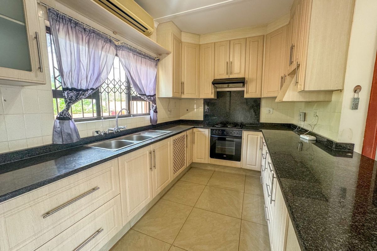 Functional kitchen featuring granite countertops, built-in oven, gas hob, extractor fan, and ample cabinetry, providing a practical workspace for daily cooking.
