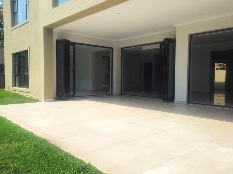 Spacious covered patio featuring large format floor tiles and modern stacking doors, providing seamless indoor-outdoor flow to the garden.