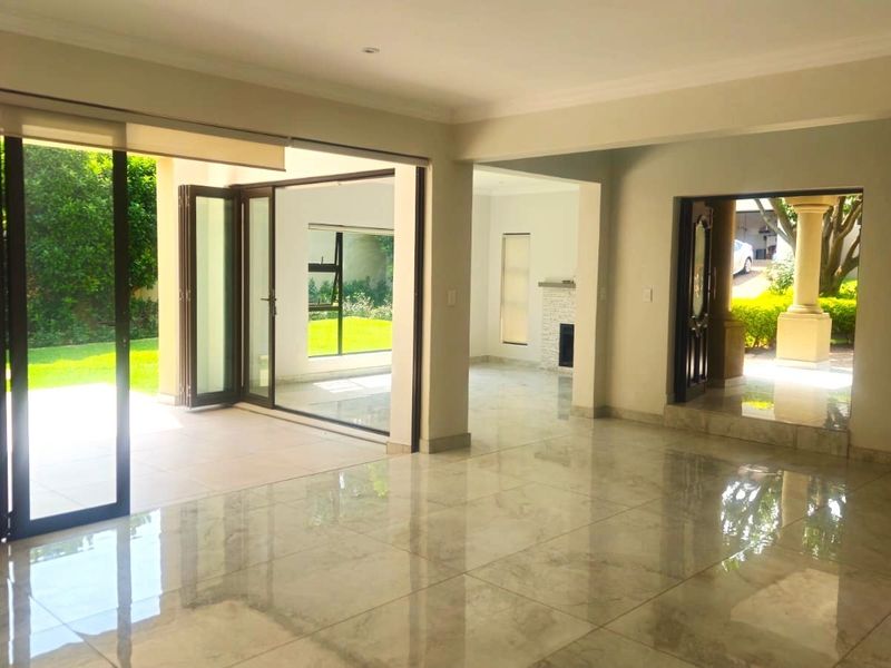 Spacious open-plan living area featuring polished tiled floors, recessed lighting, and large stacking doors providing seamless access to the outdoor patio and garden.