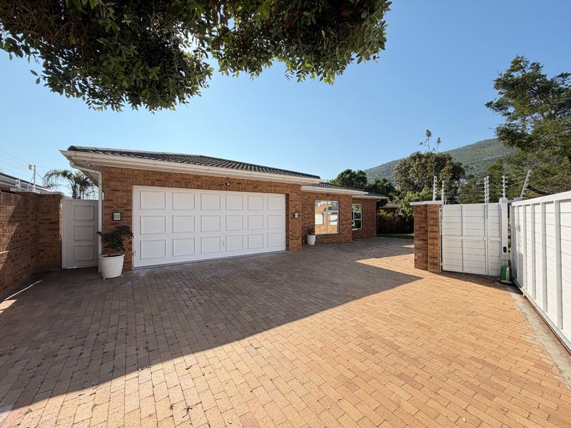 Front exterior view of the property featuring a paved driveway, double garage, and secure perimeter fencing.