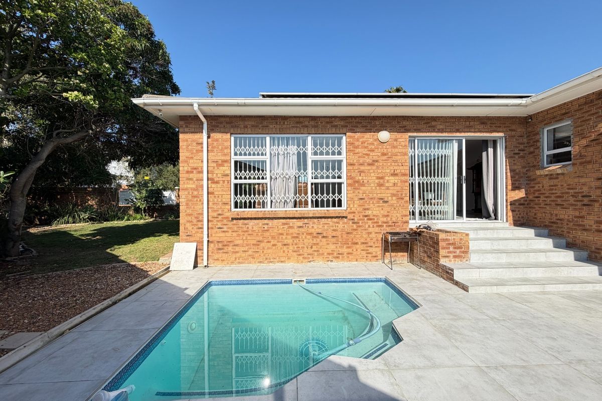 Rear exterior view featuring a swimming pool, tiled patio area, brick facade, and sliding glass door access to the home.