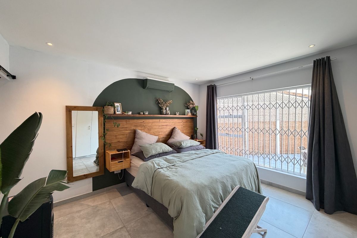 A well-maintained bedroom featuring tiled flooring, recessed lighting, an air conditioning unit, and a custom built-in headboard with integrated shelving.