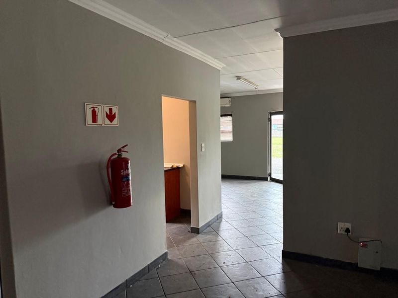 An open-plan industrial utility space featuring tiled flooring, coved cornicing, and essential fire safety equipment, providing a functional and accessible layout.