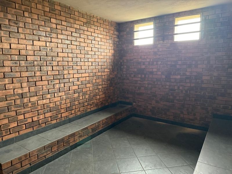 A functional utility space featuring exposed brick walls, tiled flooring, and built-in tiled bench seating, suitable for various industrial or storage purposes.