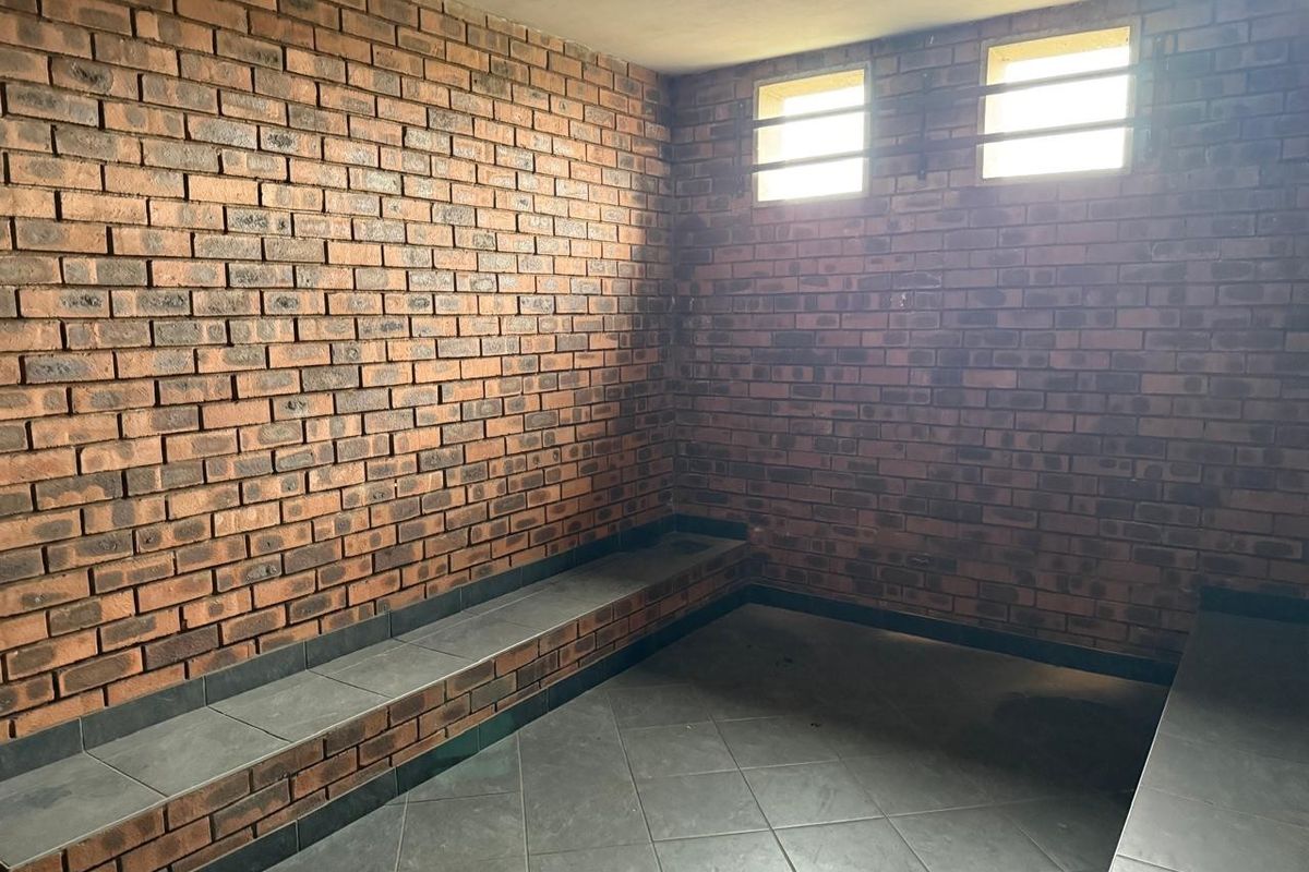 A functional utility space featuring exposed brick walls, tiled flooring, and built-in tiled bench seating, suitable for various industrial or storage purposes.