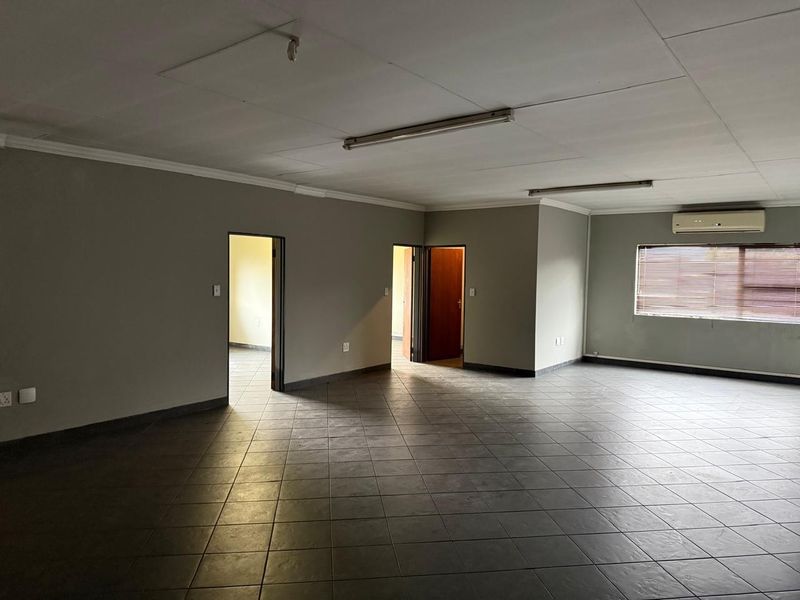 Spacious, empty office area featuring tiled flooring, split-system air conditioning, and neutral wall finishes, suitable for a professional workspace.