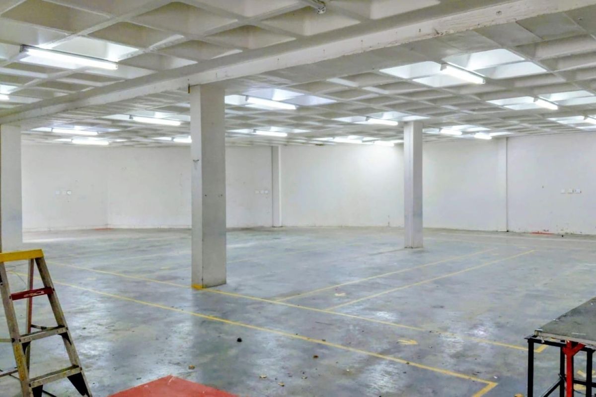 A large, open-plan industrial utility space featuring a waffle slab ceiling, concrete columns, and painted concrete flooring with marked bays.